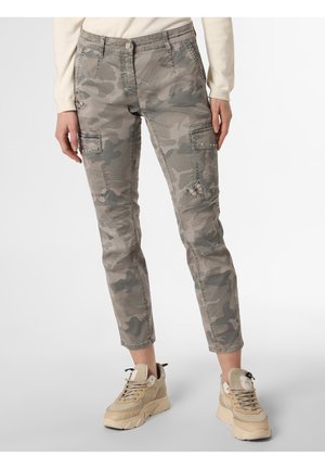 Person wearing beige camouflage cargo pants with pockets and butterfly embroidery, paired with beige chunky sneakers and a light long-sleeve top.