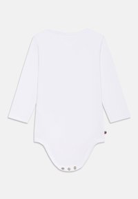 Weißer Langarm-Body mit rundem Ausschnitt und Druckknopfverschluss im Schritt. Weicher Baumwollstoff mit glatter Textur.