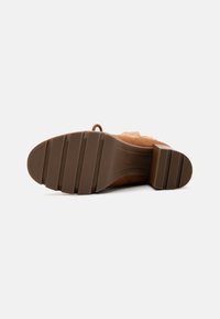 Brune semelles en daim avec une texture en caoutchouc moulé. Comprend un talon empilé et un bout lisse et arrondi. Design simple et sans décoration.