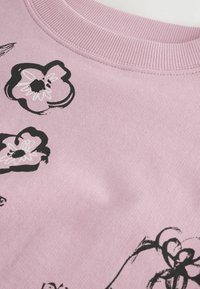Felpa in cotone rosa con colletto a coste, caratterizzata da motivi floreali neri. Tessuto morbido, vestibilità leggermente ampia e stile casual.