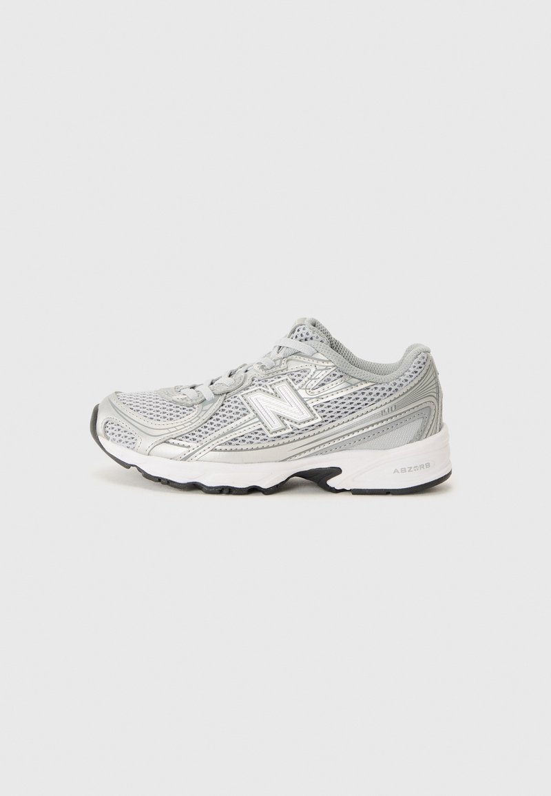 Idrettssko med overdel i mesh i sølv og grå, med en dempet såle, rund tå, og fremtredende "N"-logo på siden.