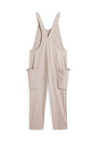 Beige Latzhose mit breiten Trägern, V-Ausschnitt, zwei großen Fronttaschen und glatter Stofftextur. Schlicht und funktional im Stil.