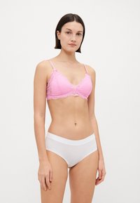 Rosa spetsbralette med justerbara remmar och en mjuk textur, tillsammans med vita åtsittande trosor med en slät midjeresår.
