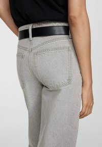 Grå denimjeans med en avslappnad passform, med bakfickor, bälte i svart läder och en texturerad yta.