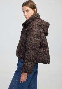 Bruin luipaardprint pufferjack met capuchon, ritssluiting en twee voorzakken. Heeft een cropped ontwerp en een puffy textuur.