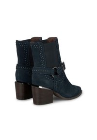 Botas de ante a la altura del tobillo en azul marino, con acentos de tachuelas y una correa con hebilla. Tacón cuadrado con textura de madera y diseño de punta afilada.