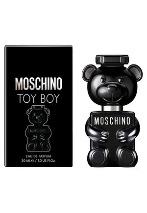 De geurflacon Black Moschino Toy Boy, gevormd als een teddybeer die een bord met de tekst "MOSCHINO" vasthoudt, naast de bijpassende zwarte doosverpakking.