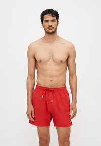 Rote Badehose mit elastischem Bund und Kordelzug, ausgestattet mit einer glatten Textur und einem lässigen Schnitt, geeignet für Wasseraktivitäten.