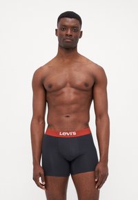 Svarta kalsonger med en röd Levi's-logotyp som midja, tillverkade av mjukt tyg, med en åtsittande passform och en enkel design. Inga märkbara mönster eller accenter.