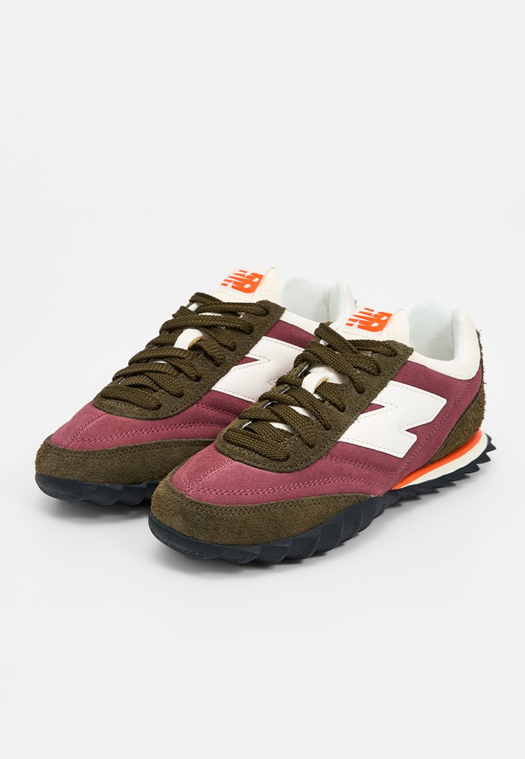 Zapatillas New Balance con parte superior de ante burdeos y oliva, detalles en blanco y suela exterior de goma negra resistente con acentos en naranja.