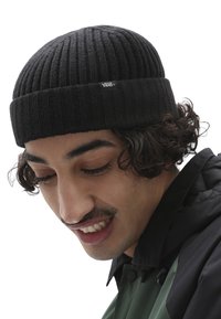 Berretto in maglia nera con texture a coste, risvoltato e dotato di una piccola etichetta con il logo Vans sul davanti.