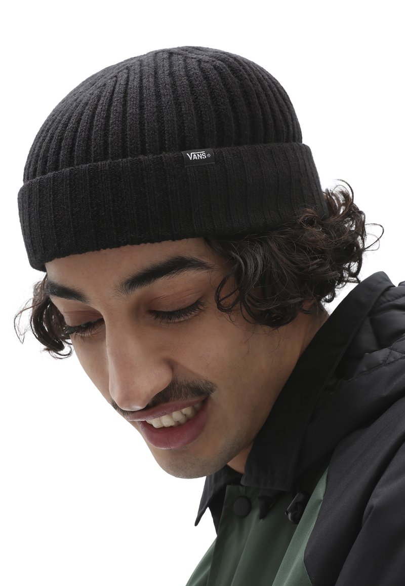 Berretto in maglia nera con texture a coste, risvoltato e dotato di una piccola etichetta con il logo Vans sul davanti.