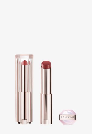 Roze getinte lippenstift in een slank, glanzend metalen buisje naast een roze, hexagonale compact met zilveren branding. Helder omhulsel met verticale strepen.
