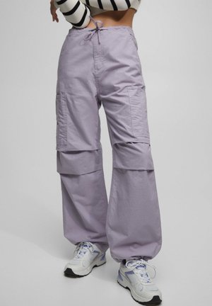 Lila cargobroeken met een trekkoord in de taille, twee zijzakken en elastische boorden. Draag ze met witte sneakers met subtiele blauwe accenten.