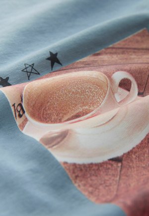 Material de culoare albastru deschis cu un imprimeu grafic cu o cană și farfurie bej, având o suprafață texturată, stele negre îndrăznețe și o nuanțare detaliată.