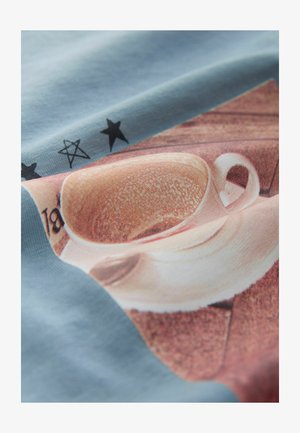 Lichtblauwe stof met een grafische print van een beige kop en schotel, met een textuur, gedurfde zwarte sterren en gedetailleerde schaduwwerking.