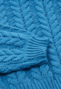 Strickstoff in Blau, der durch erhöhte Zopfmuster und gerippte Bündchen besticht. Weiches, strukturiertes Material in einer lebendigen, einfarbigen Ausführung.