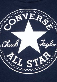 Granatowy materiał z białym graficznym logo z napisem "CONVERSE ALL STAR" oraz gwiazdką na środku, udekorowany stębnowaniem.