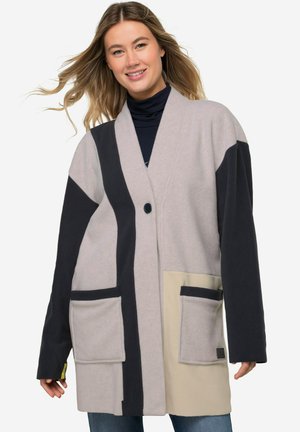 Cardigan in morbido pile grigio chiaro, blu navy e crema. Presenta una vestibilità rilassata, due tasche frontali, chiusura a un bottone e design senza colletto.