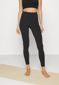Fekete, magas derékú leggings rugalmas anyagból, sima, elegáns kialakítással, látható minták vagy fémrészek nélkül.