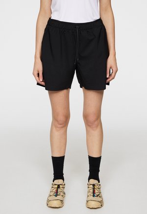 Schwarze Sportshorts mit einem elastischen Bund und Kordelzug. Sie haben einen lockeren Schnitt, eine glatte Textur und seitliche Schlitzdetails.