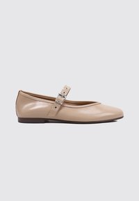 Bailarina de cuero beige con punta redonda, suela plana y una correa decorativa con hebilla metálica en el empeine. Textura suave.