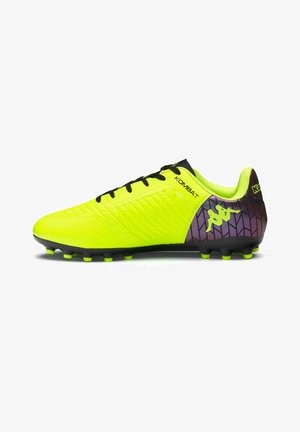 Crampon de football jaune néon et noir avec des lacets noirs, côté texturé et talon violet arborant un logo jaune et le mot « KOMBAT ».