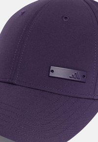 Purple cap with a smooth fabric texture, featuring a flat brim and a rectangular logo patch on the front. Subtle stitching detail visible.