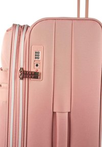 Maleta rígida rosa con superficie texturizada, doble cremallera, candado de combinación y acentos del logo de DKNY en los tiradores de las cremalleras.