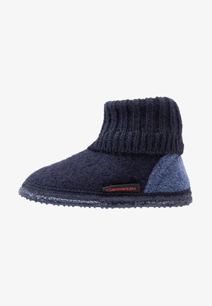 Wollen pantoffels in blauw en marine, met een ribbelgebreide boord en vilten accenten. Gelaagd oppervlak, ronde neus en rubberen zool.