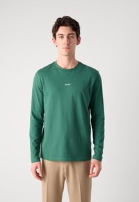 Zöld, hosszú ujjú póló puha anyagból, crew neck kivágással és a mellkas közepén elhelyezett kis "BOSS" logóval.