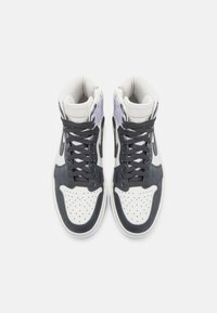 Baskets montantes en cuir blanc avec des accents bleu marine, présentant une boîte à orteils perforée, des lacets gris et des détails violets sur le col.