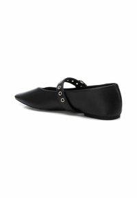 Zapato plano negro con punta afilada, hecho de piel suave. Cuenta con una correa con ojales metálicos. Diseño de bajo perfil y mínimos detalles.