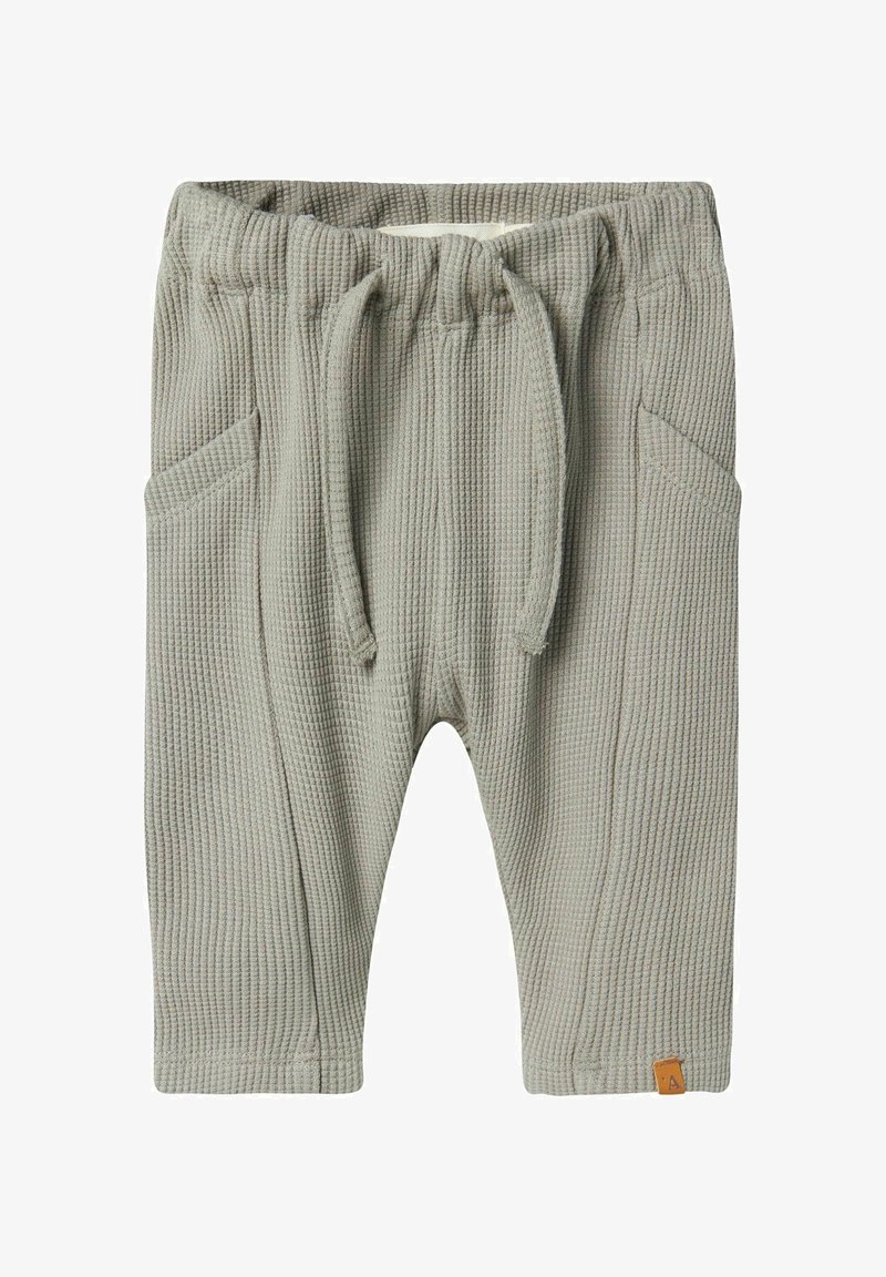 Pantalon gris clair pour tout-petit avec texture gaufrée, taille élastique, cordon, poches latérales et petite étiquette logo marron sur la partie basse de la jambe.