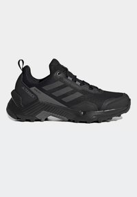 Chaussure de trail running Adidas Terrex noire avec semelle robuste, tige en mesh, fermeture à lacets et languette au talon.