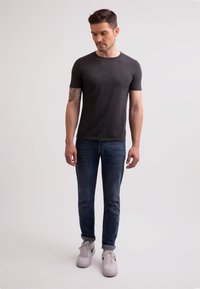 Tyrkysové krátký rukáv tmavě šedé tričko spárováno s modrými džíny a bílými teniskami. Tričko má slim fit a kulatý výstřih.