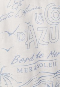 Tela blanca con texto en francés en azul claro, gaviotas, palmera y olas que ilustran un tema costero de verano.