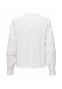 Blouse blanche à manches longues avec détails en dentelle autour des manches mi-longues et poignets boutonnés, vue de dos sur un fond uni.