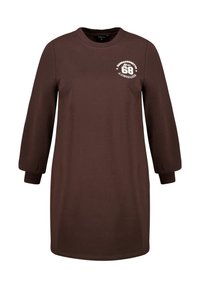 Bruine katoenen jurk met lange mouwen, ronde halslijn en geribbelde manchetten. Voorzien van een witte grafische print op de bovenste linkerborst.