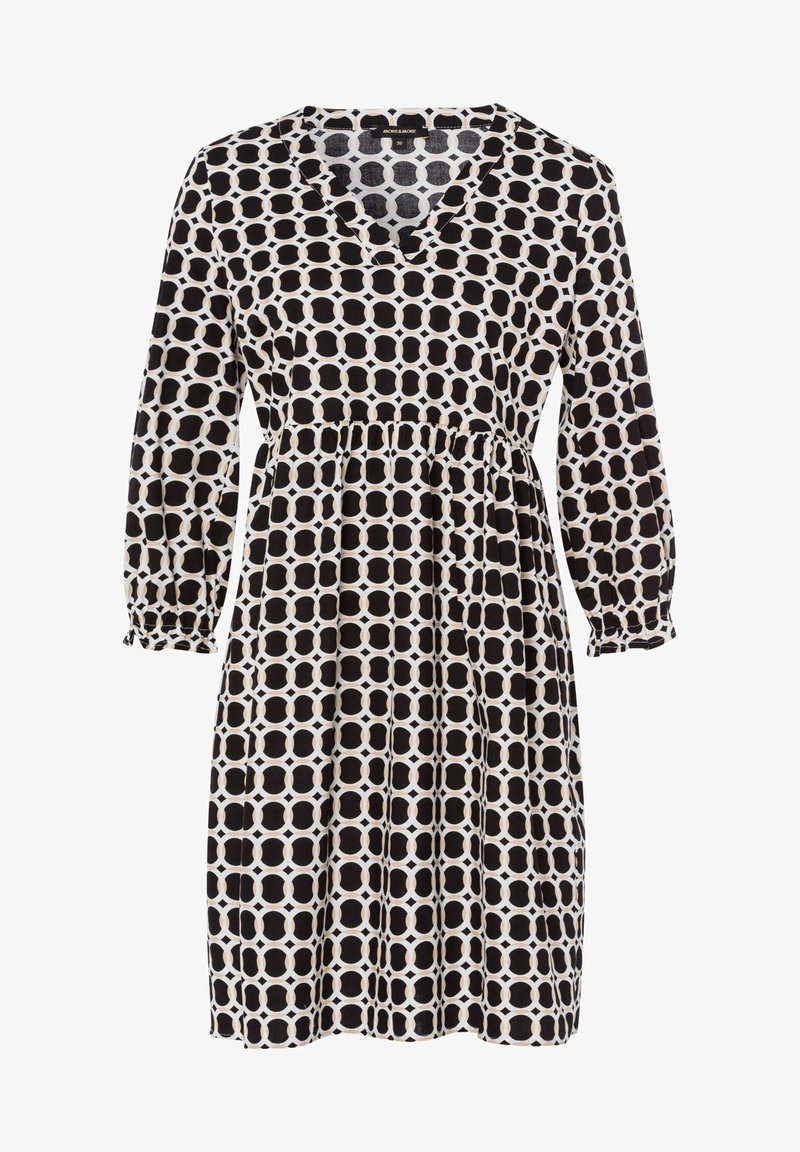 Černobílé šaty se vzorem, mají V-výstřih, dlouhé rukávy, elastické manžety a nařasený pas. Obsahují osmiúhelníkový geometrický vzor.