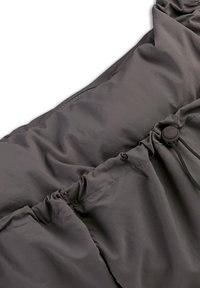 Grijs polyester stof met een geplooide textuur, trekkoorddetail en een knopaccent nabij de rand. Soepel, lichtgewicht en naadloos ontwerp.