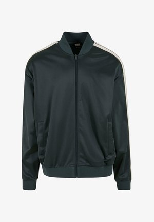 Giacca bomber verde scuro realizzata in tessuto liscio e lucido. Dotata di zip frontale, due tasche laterali e strisce bianche sulle spalle.