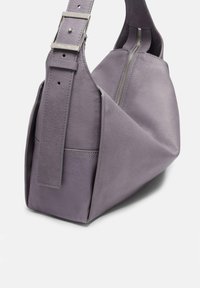 Lila Lederhandtasche mit geometrischem Design, ausgestattet mit einem breiten Trageriemen und silbernen Beschlägen. Glatte Textur und dezente Nahtdetails.