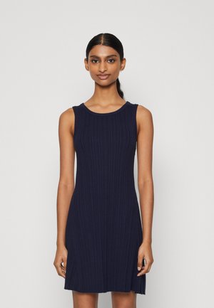Robe sans manches bleu marine avec une texture côtelée, un col rond et un ourlet évasé. Fabriquée en tissu tricoté, conçue pour une silhouette ajustée.