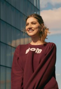 Bordeaux sweatshirt met een ronde hals en pluchen witte geborduurde tekst. Zachte stof met een ontspannen pasvorm, voorzien van lange mouwen en subtiele stiksels.