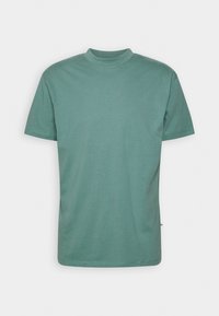 T-shirt manches courtes en vert doux, col rond, en coton doux, avec une petite étiquette latérale et une coupe décontractée.