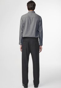 Gray striped button-up shirt with a collar and long sleeves, paired with dark gray tailored trousers. Features rear pockets and a relaxed fit.