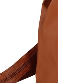 Bruine leren tas met een gladde textuur, een gebogen vorm en een zichtbare ritssluiting aan de zijkant met contrasterende stikseldetails.