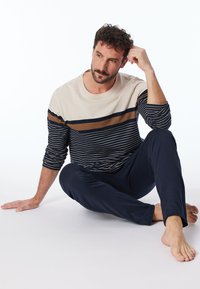 Langärmliges Hemd in Blau und Beige mit horizontalen Streifen und passenden marineblauen Hosen. Glattes Material, lockere Passform und schlichtes Design.