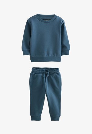 Kék hosszú ujjú pulóver kisgyermekeknek, hozzáillő zsinóros melegítőnadrággal, bordázott mandzsettákkal és derékrésszel, fehér háttéren.